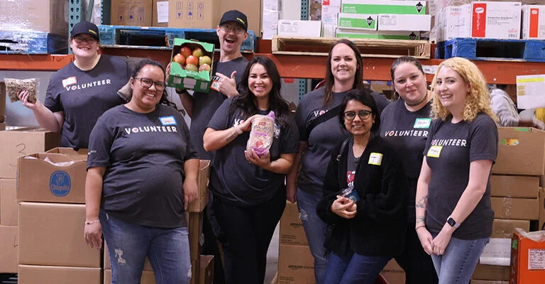 Group of volunteers in a warehouse setting with boxes and produce.