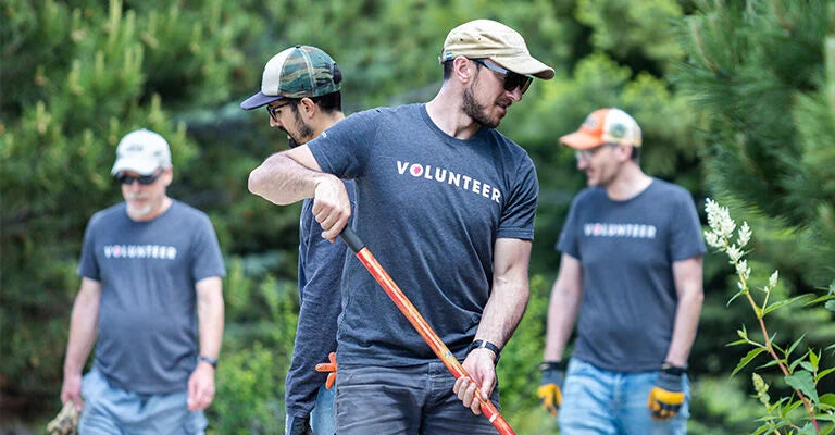 Group of volunteers in matching shirts with a tree in the background