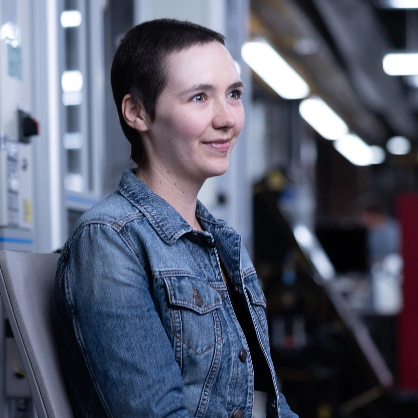 Person wearing a denim jacket in an industrial setting