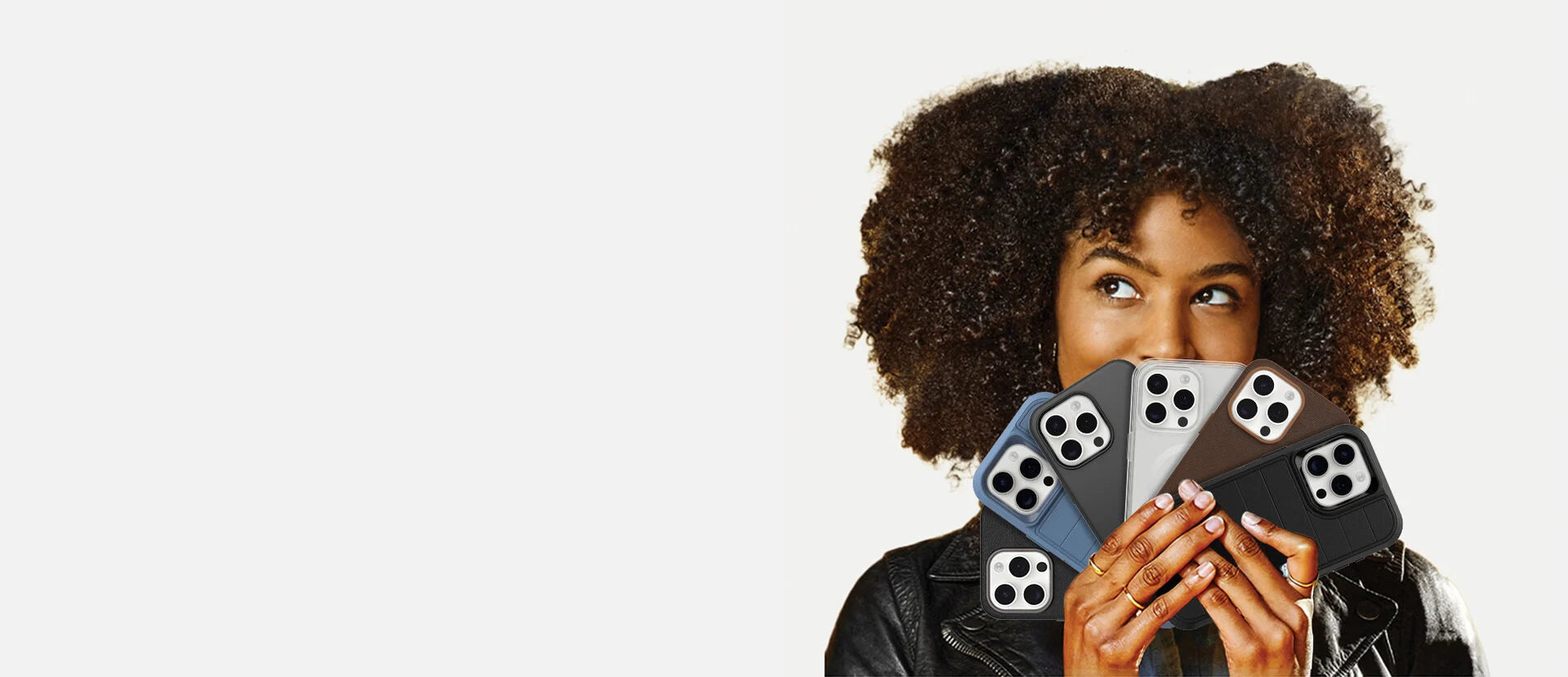 Person holding four smartphone cases in front of their face on a white background