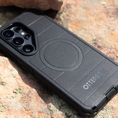 Black Samsung OtterBox phone case on a rocky surface