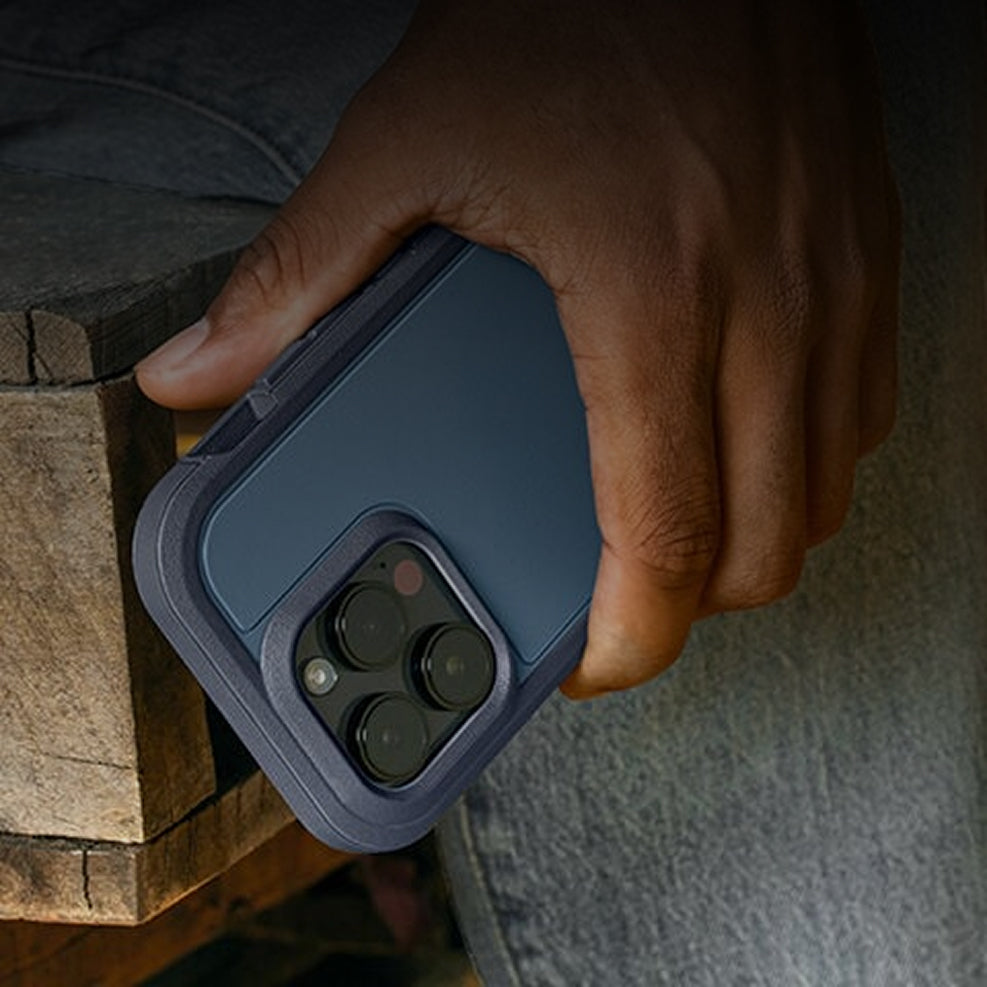 Hand holding a blue phone case with a wooden surface in the background